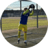 Fußballtorwart in gelber Hose und blauem Trikot fängt einen Ball vor dem Tor auf einem Kunstrasenplatz.