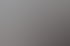 Große Gruppe von Menschen posiert lächelnd in einem hellen Raum mit Holzfußboden und großen Fenstern.