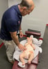 Chiropractor examining a baby girl lying on a chiropractic table.