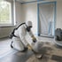 Fachkraft in Schutzanzug und Atemschutz entfernt bei einer Asbestsanierung in Köln alte Floor-Flex-Platten in einem mit Folie abgeschotteten Raum mit Unterdruckgerät