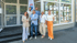 Sechs Immobilienmakler posieren lächelnd vor einem RE/MAX Immobilienbüro mit Schaufensteraushängen.