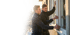 Zwei Handwerker in schwarzen Pullovern montieren ein Fenster in einem Gebäude.