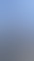 Drei Wanderer auf einem felsigen Berggipfel, umgeben von einem mit Aufklebern bedeckten Mast unter blauem Himmel.