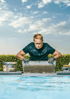 Handwerker setzt eine Fliese mit Fliesenkleber am Rand eines Swimmingpools ein.
