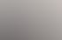 Drei Personen in Business-Kleidung stehen lächelnd in einem modernen Büro vor Computerarbeitsplätzen.