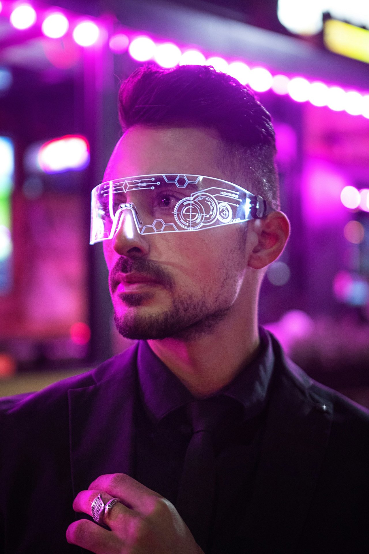 Mann mit Bart trägt eine leuchtende Cyberpunk-Brille mit HUD-Grafiken vor violettem Neonlicht.