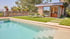 Moderner Swimmingpool mit Rasenfläche, Sonnenliege und einem Gartenhaus mit Außenbar und großen Glasfronten.