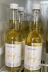 Mehrere Glasflaschen Lexengut Apfelmost mit weißen Etiketten und goldenem Text stehen in einem Kühlschrank.