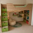 Ein Kinderzimmer mit einem Hochbett aus hellem Holz, grünen Schubladen, Bücherregalen und einer Lichterkette.