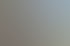 Ein leerer Balkon mit braunen Fliesen und einem Metallgeländer, der auf ein angrenzendes Gebäude und Bäume blickt.