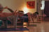 Drei Frauen üben in einem warm beleuchteten Raum die Yoga-Pose Vogel-Hund auf ihren Matten aus.