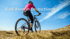 Frau auf Mountainbike, auf einem Hügel mit blauem Himmel, Text: Radfahren in Deutschland