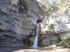 Zwei Personen in Schutzkleidung seilen sich einen Wasserfall in einer Felsenschlucht ab.