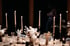 Festlich gedeckter Tisch mit brennenden Kerzen und Blumenarrangements bei Nacht.