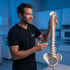 chiropractor points to a spine model as he explains spinal health.