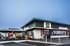 Modernes McDonald's Restaurant mit dunkelgrünem Dach, brauner Holzverkleidung und goldenem M-Logo.