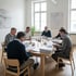 Wohnungseigentümer mit Tagesordnung an einem Tisch im Gemeinschaftsraum