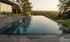 Ein Infinity-Pool auf einer Terrasse bei Sonnenuntergang mit Blick auf eine bewaldete Hügellandschaft.