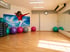 Ein Fitnessraum mit Parkettboden, bunten Gymnastikbällen, Step-Boards, einer großen Wandspiegelung und einem Wandbild.