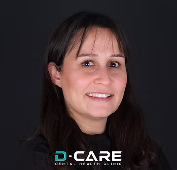 Lächelnde Frau mit dunklen Haaren vor schwarzem Hintergrund, unten links "D-CARE DENTAL HEALTH CLINIC" Logo.