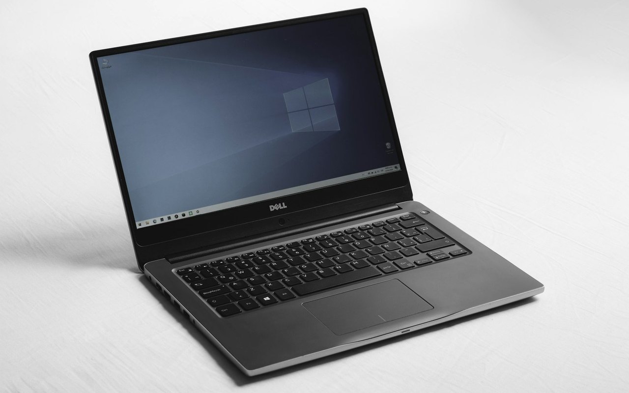 Aufgeklappter Laptop mit Windows-Startbildschirm auf einer weißen Fläche