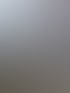 Außenwand eines Gebäudes mit Klimaanlage, Abluftrohr, und mehreren großen silbernen Rohren über Kiesboden.