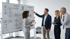 Vier Personen stehen vor einem Whiteboard mit einem Flussdiagramm und dem Text "ISO 9001 Anforderungen".