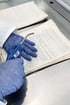 Eine Person mit Handschuhen besprüht ein altes Buch mit einem blauen Sprühgerät.