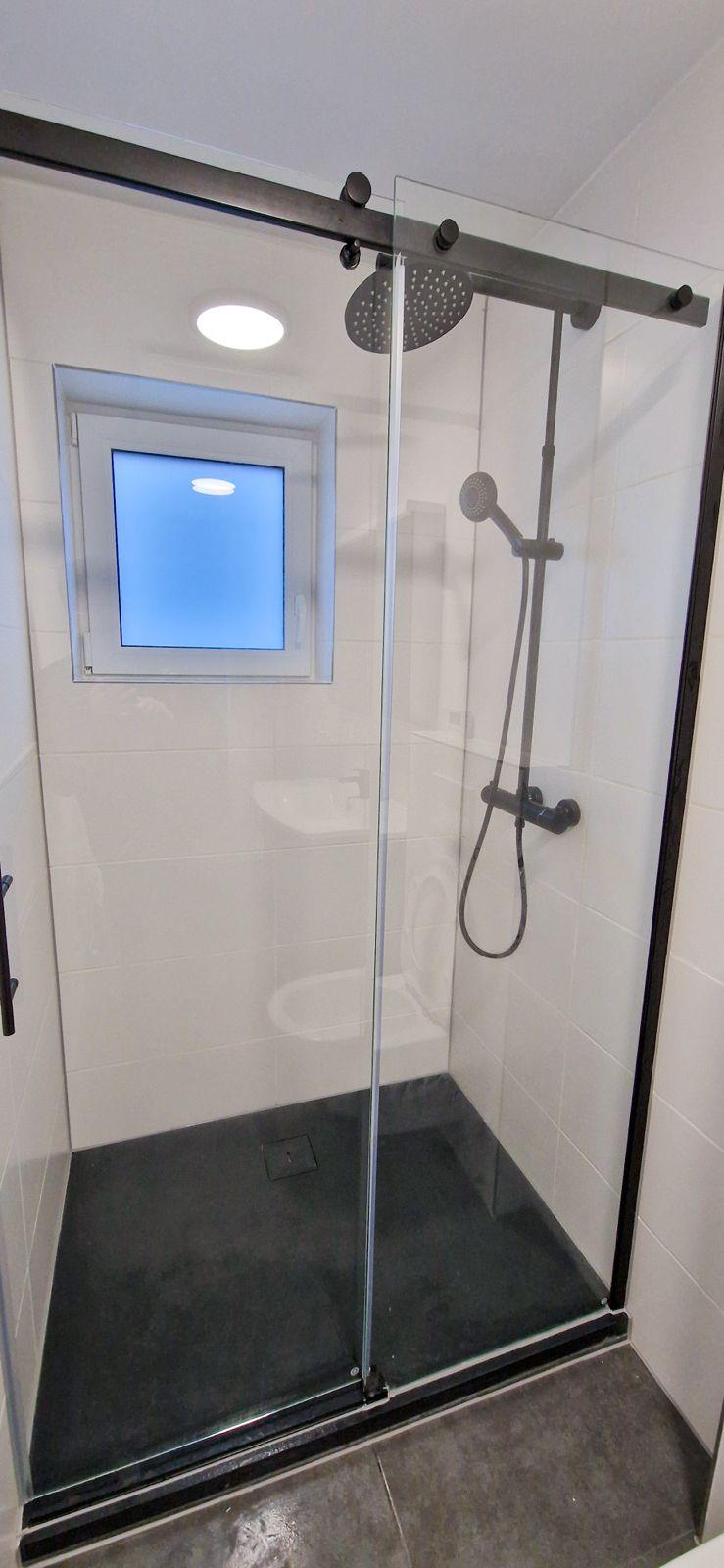 Bodengleiche Dusche mit gläserner Schiebetür und Regenbrause
