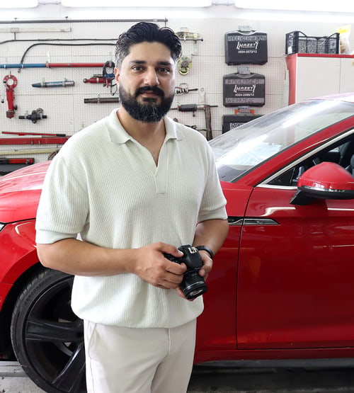 KFZ-Sachverständiger Sobeir Esmaty mit Kamera zur Schadendokumentation in der Werkstatt in München