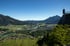 Blick von oben auf ein Tal mit einem Fluss, der sich durch eine Stadt schlängelt, umgeben von Bergen.