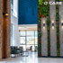 Lobby mit Ziegelwand, vertikalem Garten und blauer 3D-Wand, D-CARE Logo oben rechts.