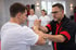 Zwei Männer üben Wing Chun, Hände verschränkt, andere Schüler beobachten im Hintergrund.