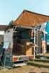 Individuell gestalteter Seaside Camper mit Holzelementen, offenem Sonnendach und Blick auf die modularen Innenmöbel bei einer Outdoor-Ausstellung.