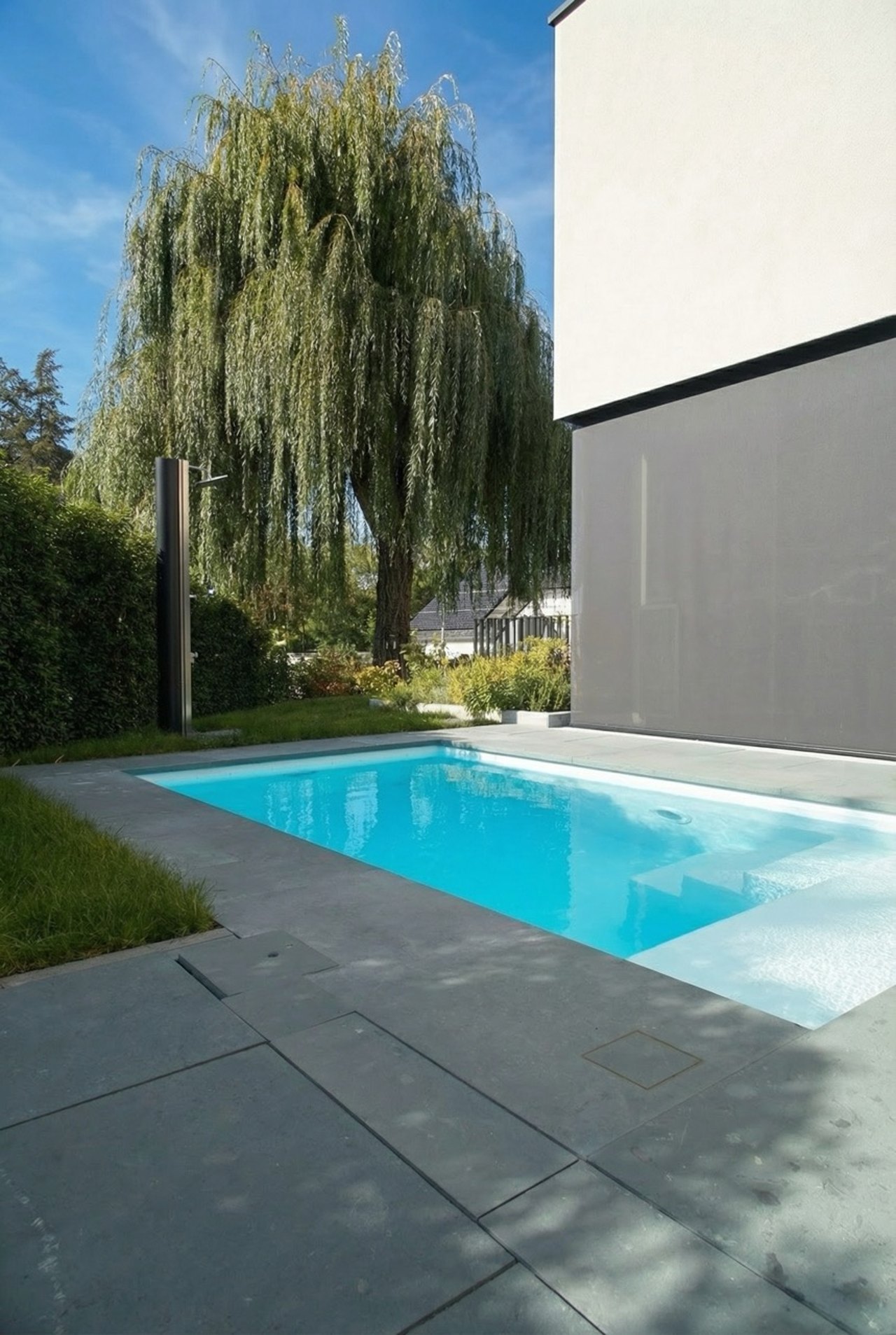 Swimmingpool mit hellblauem Wasser im gepflegten Garten