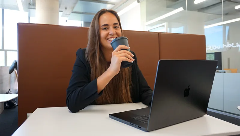 Alexandra im Videocall am Laptop mit Kaffeebecher