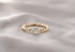 Goldener Verlobungsring mit geflochtener Ringschiene und einem runden Diamanten auf hellem Seidenstoff.