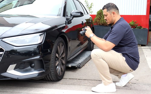 KFZ-Gutachter Jawid Rahimi fotografiert einen Unfallschaden am vorderen Radlauf eines Fahrzeugs in München