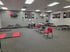 Physical therapy room with treatment tables, red chairs, and exercise equipment.