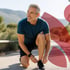 Gray-haired man ties black shoes, a smile for his orthobiologics run.