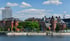 Berliner Stadtlandschaft mit Gebäuden aus rotem Backstein am Ufer eines Flusses unter blauem Himmel.