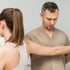 A chiropractor examines a woman's shoulder.
