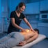 A female therapist performs a chiropractor-guided therapeutic massage on a man’s glowing lower back.
