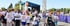 A large group of people wearing "Walk for MS" t-shirts participate in a charity walk past an outdoor event stage.