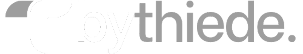 Logo mit weißem "T" und "by" und grauem "thiede." auf dunkelgrünem Hintergrund.