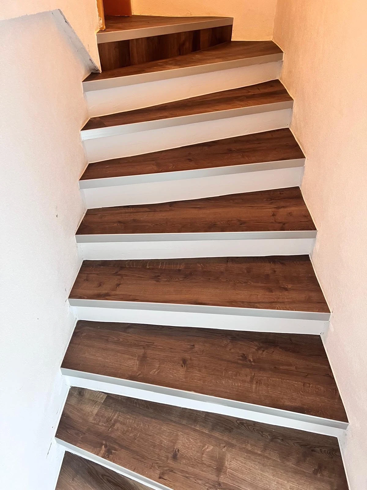 Die fertige Treppe von unten, dunkle Stufen mit weiß gestrichenen Setzstufen