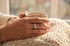 Hand mit RingConn Smart Ring hält eine Kaffeetasse auf einer Wolldecke (KI-generiertes Symbolbild)