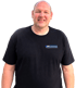Lächelnder Mann mit Glatze im schwarzen T-Shirt mit dem Logo Wingeier Trubschachen vor schwarzem Hintergrund.