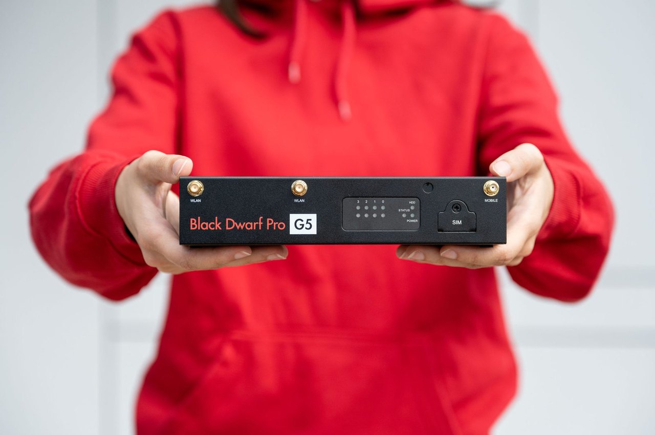 Zwei Hände halten eine Firewall Securepoint Black Dwarf Pro G5 vor einem roten Pullover