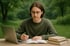 Ein junger Mann mit Brille schreibt in ein Notizbuch, daneben ein Laptop und Bücher, im Freien.